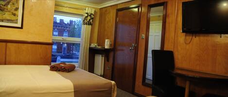 A hotel room with two beds, a television, a coffee machine, and a window with curtains.