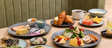A dining table with various plates of food, a cup of coffee, and a bowl of soup.