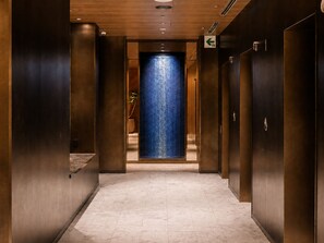 A corridor with a blue textured wall at the end, wooden paneling on the walls, and a tiled floor. - Mitsui Garden Hotel Okayama (Okayama)