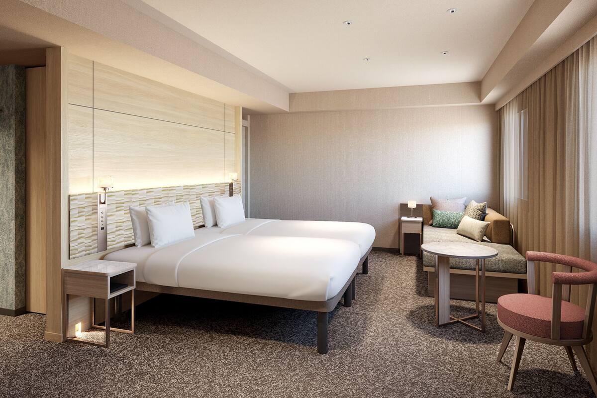 Una habitación de hotel moderna con una cama grande, una zona de estar con una mesita y una silla separada.