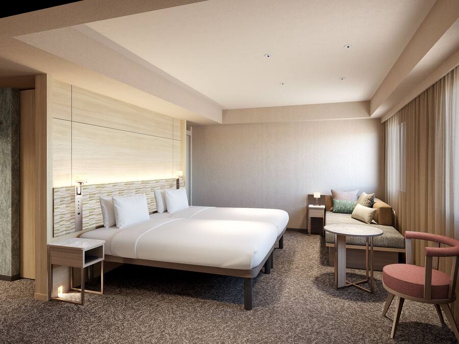 Una habitación de hotel moderna con una cama grande, una zona de estar con una mesita y una silla separada.