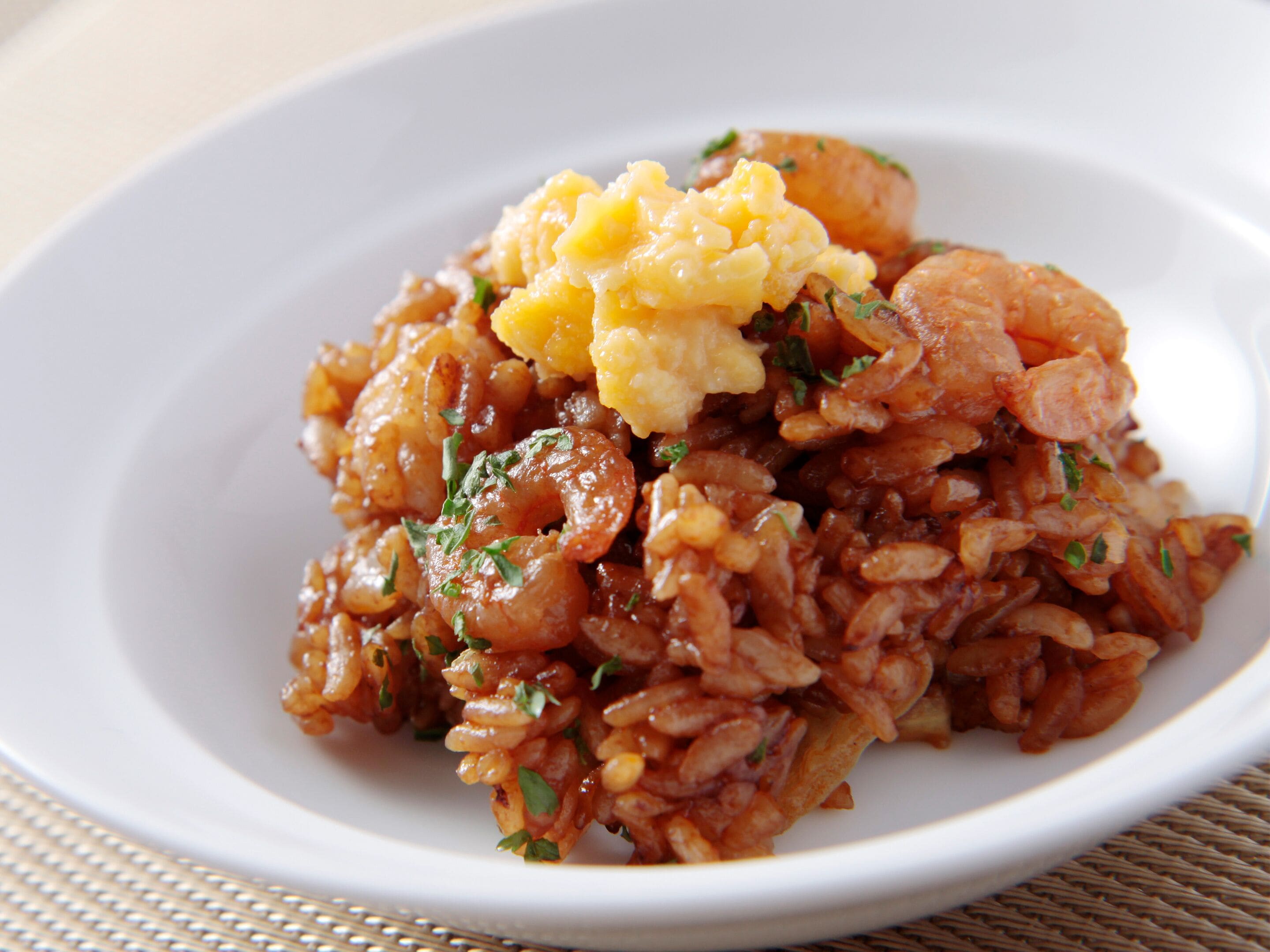 A plate of food with rice, shrimp, and scrambled eggs.