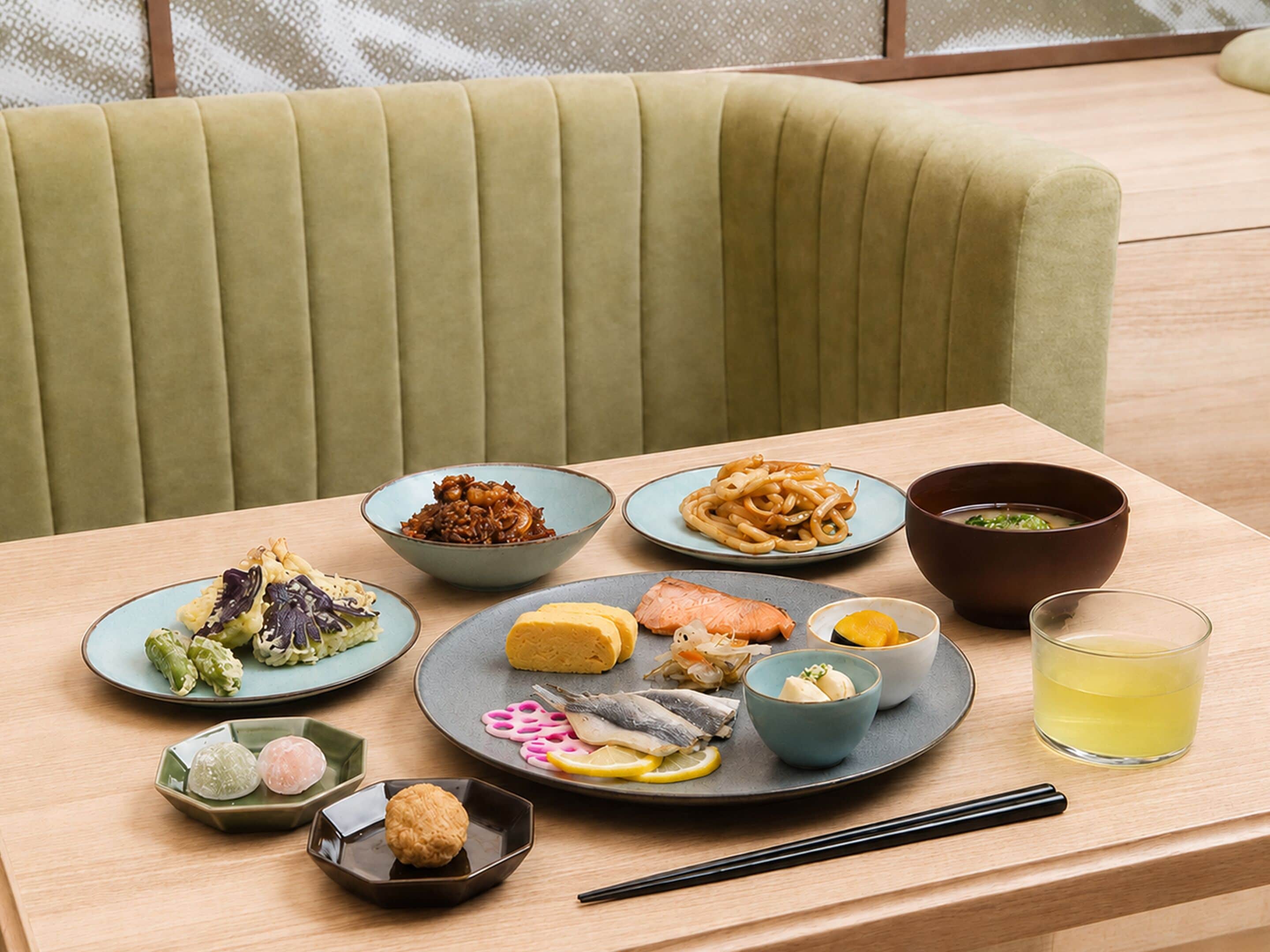 A dining table with various dishes, chopsticks, and a glass of drink.