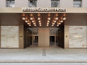 The entrance of Mitsui Garden Hotel with a modern design, featuring a marble facade and a series of illuminated panels above the entrance. - Mitsui Garden Hotel Okayama (Okayama)