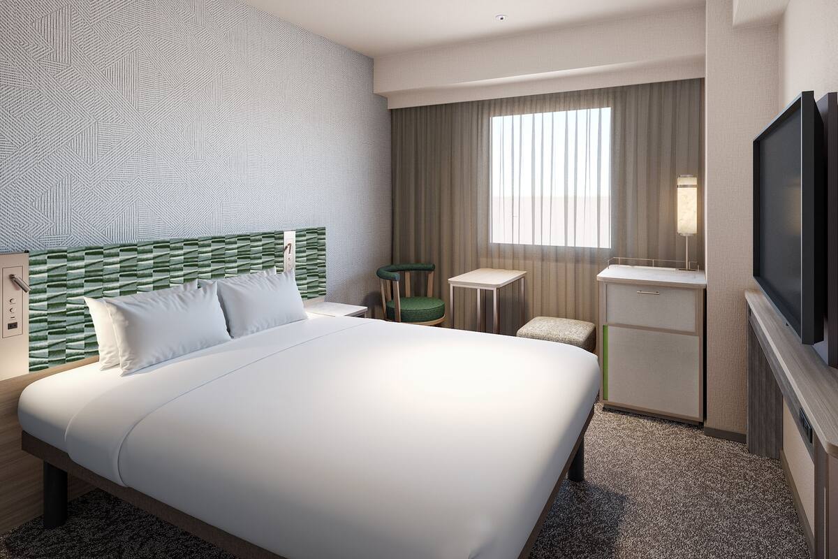 Habitación de hotel con una cama grande, un escritorio, una silla, un televisor y una ventana con cortinas.
