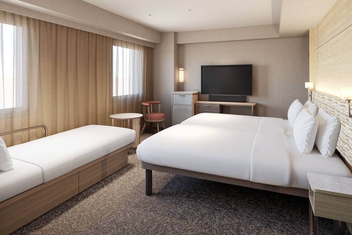 Una habitación de hotel con una cama grande, un sofá más pequeño, un escritorio, una silla y un televisor.