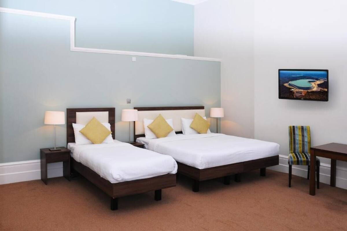 Habitación de hotel con dos camas, una mesita y una silla.