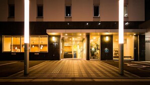 A hotel entrance with a tiled walkway, a reception desk, and a wheelchair-accessible entrance.