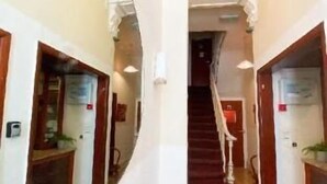 Un corridoio con pavimento in legno, pareti bianche e una scala che conduce a un altro piano.