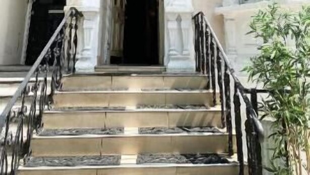 Ingresso di un hotel con un cartello che riporta 'HOTEL ORLANDO', una scala e una pianta in vaso.