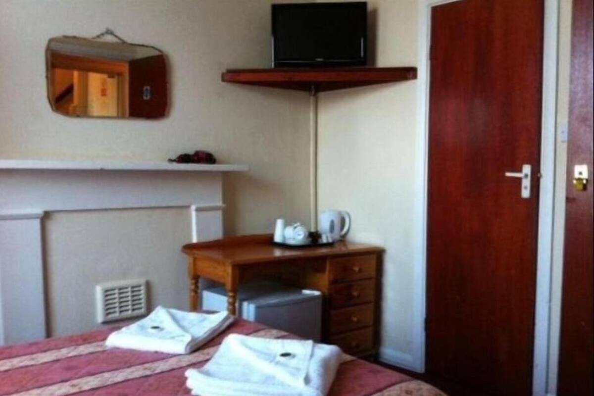 Une chambre d’hôtel avec un lit, un bureau, une télévision, une armoire et une porte.