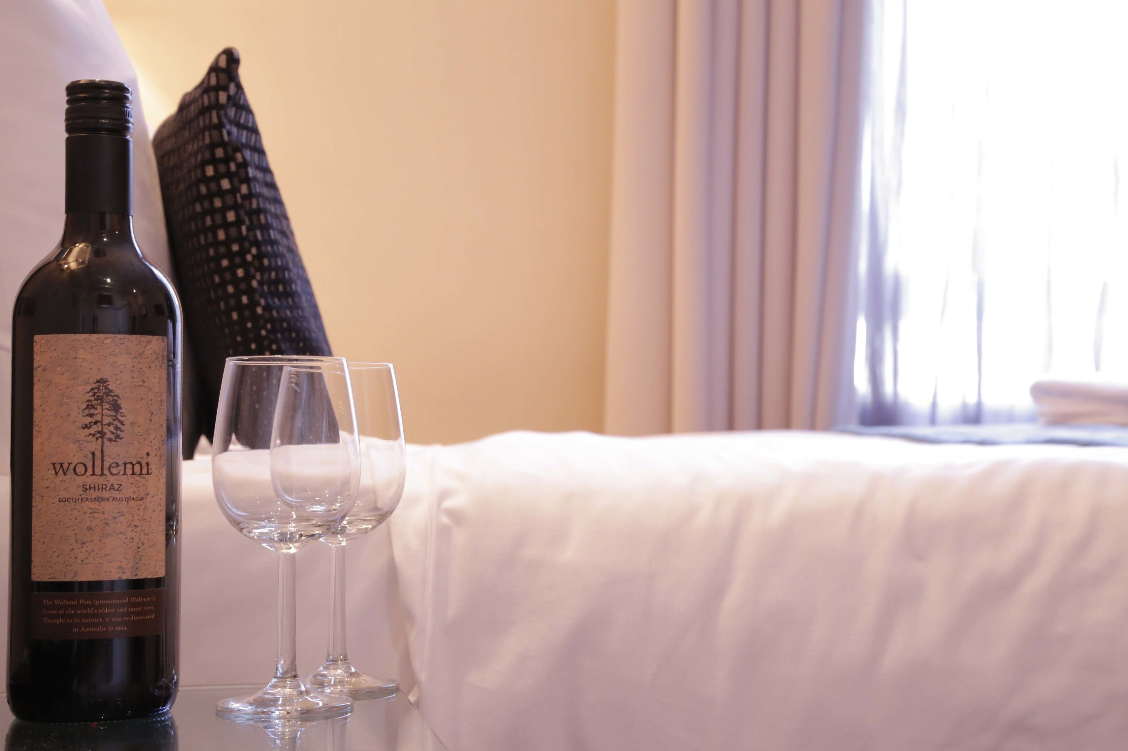A bottle of wine and two glasses on a table in a hotel room.