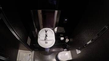 A compact bathroom with a white sink, toilet, and bidet.