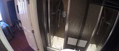 A modern bathroom with a glass-enclosed shower, a white sink, and a red patterned floor.