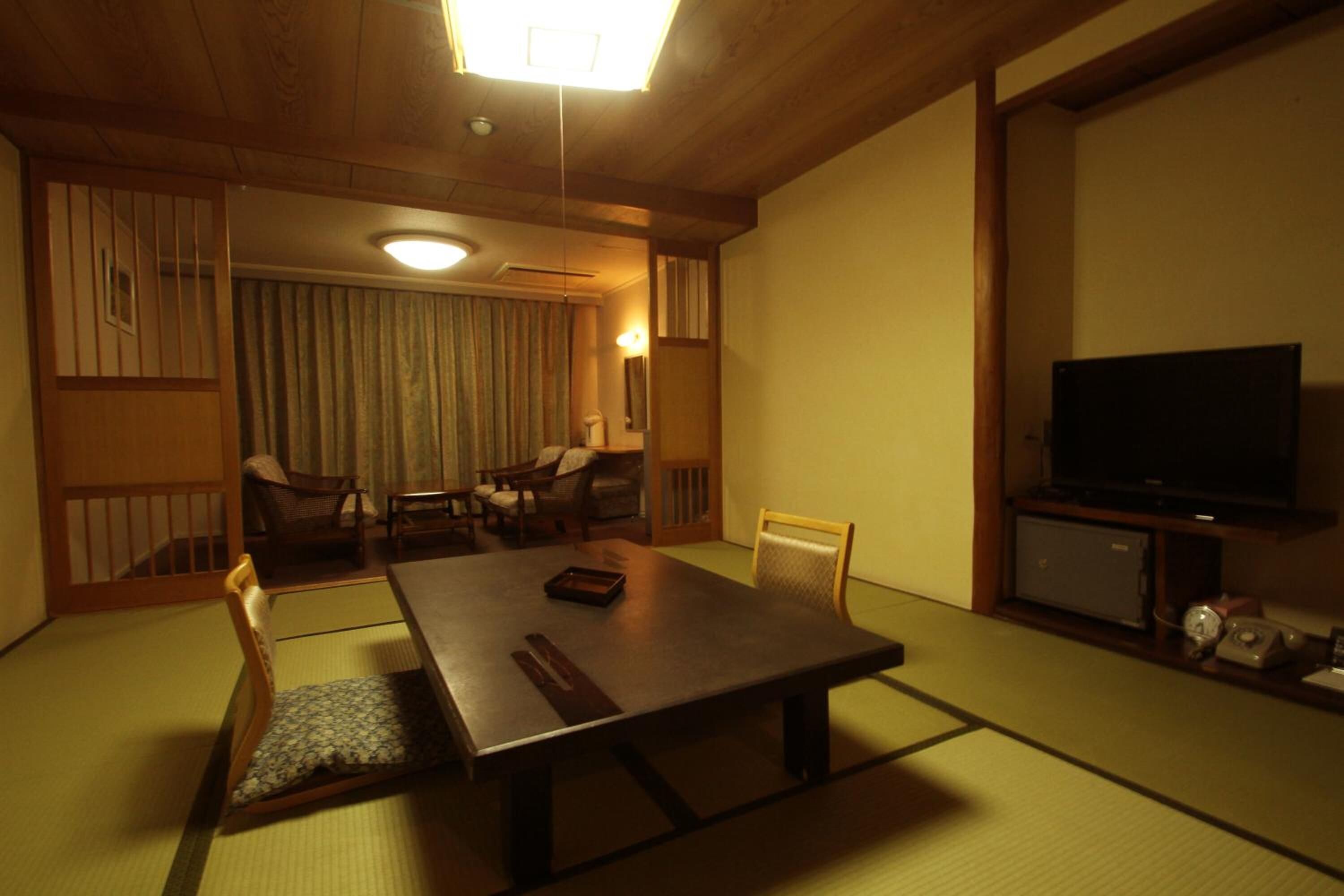 Una habitación tradicional japonesa con suelo de tatami, una mesita baja y asientos.