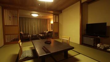 Una habitación tradicional japonesa con suelo de tatami, una mesita baja y asientos.