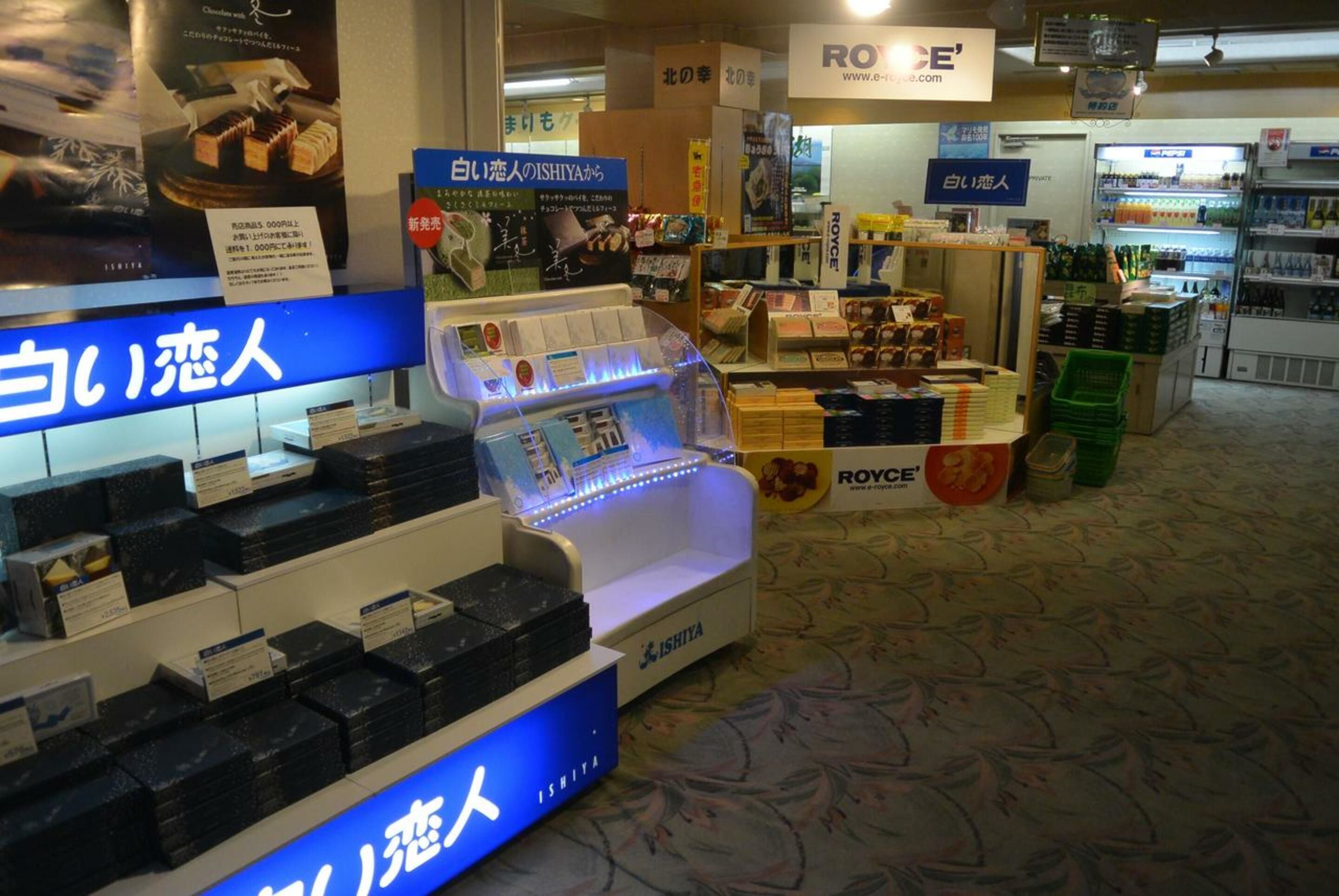 A retail store with shelves stocked with products, a blue illuminated display, and signs in a foreign language.