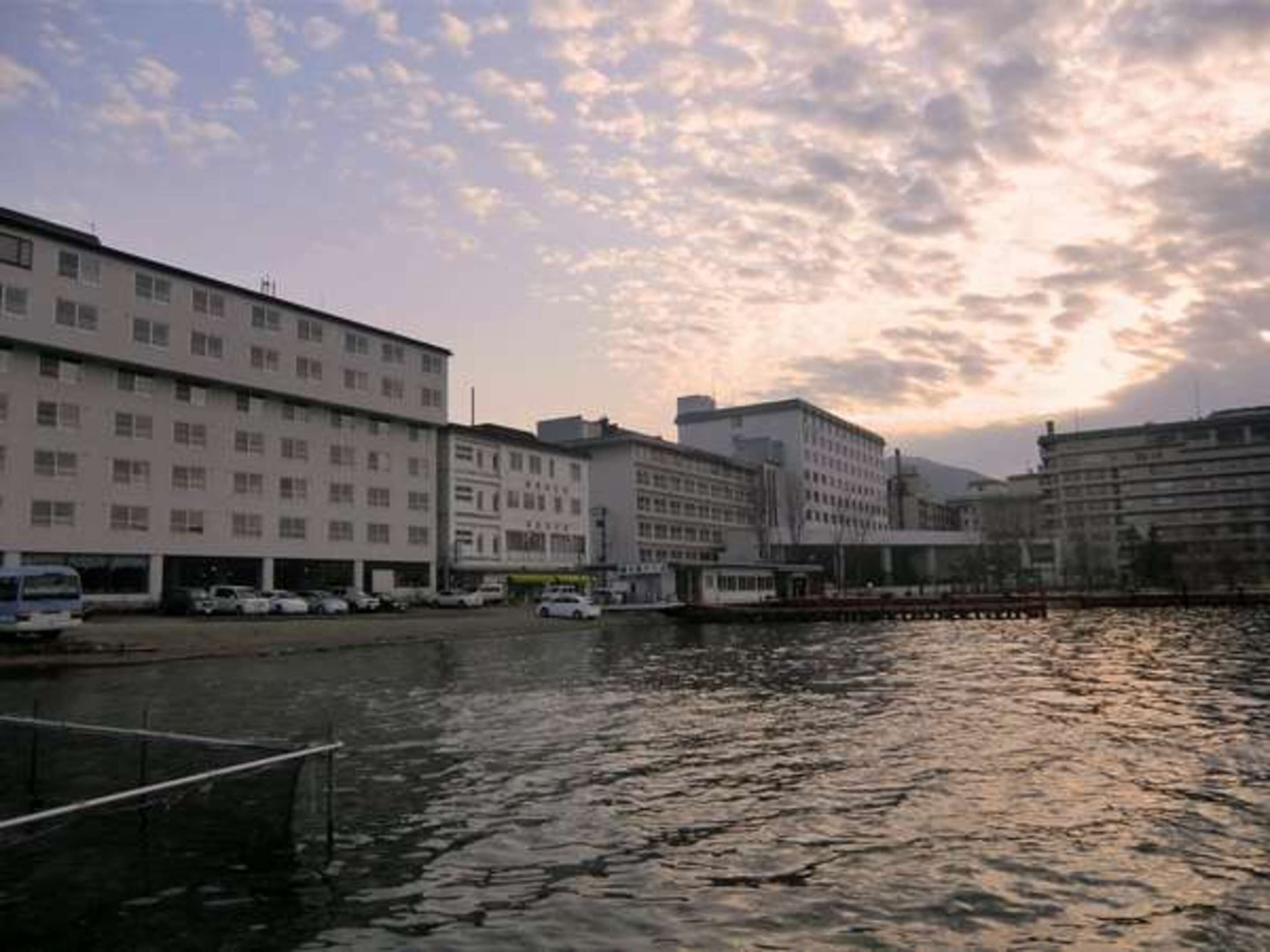 Un hotel frente al río, con varias edificaciones, un muelle y un río tranquilo.