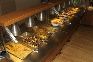 Un bufé con múltiples estaciones de comida, incluyendo fideos, verduras y diferentes tipos de carne.