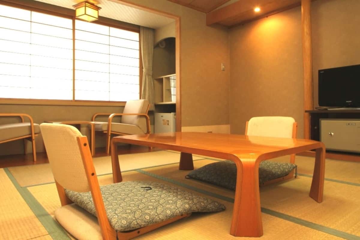 Ett traditionellt japanskt rum med tatamimattor p å golvet, ett lågt träbord och två stolar med kuddar.