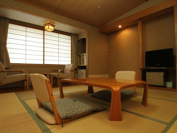 A traditional Japanese-style room with tatami flooring, a low wooden table, and tatami mat seating.