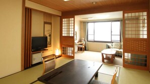 Een traditionele Japanse kamer met tatami vloeren, een lage tafel, een televisie en schuifdeuren.