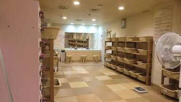 A room with a checkered floor, wooden shelves, a fan, and a counter with stools.