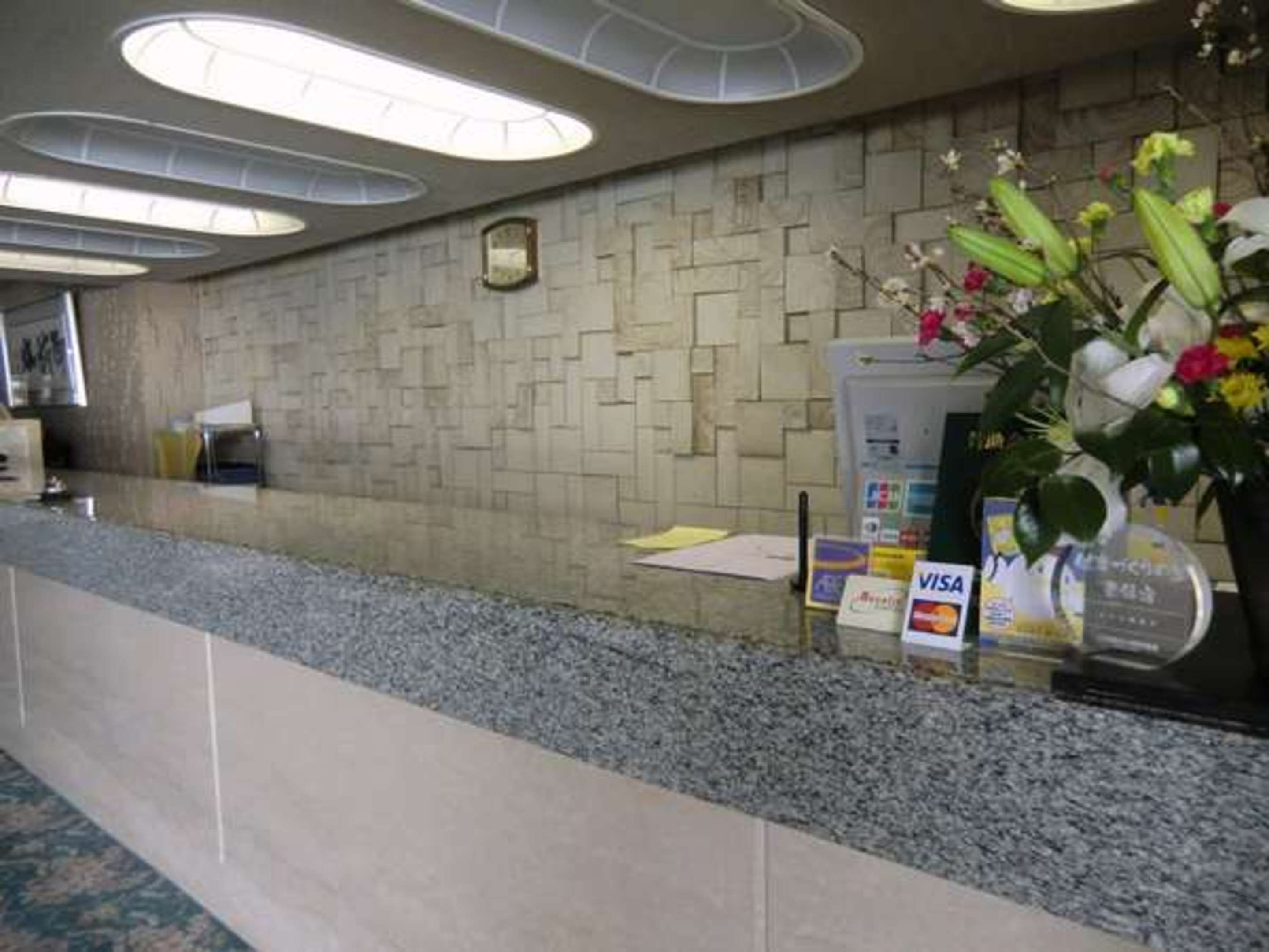 Zona de recepción con pared de piedra, mostrador y señal de Visa.