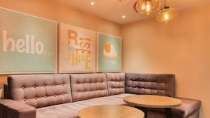 A modern lounge area with a sectional sofa, two round tables, and motivational wall art. - Premier Inn London Beckton (London)