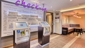 A hotel lobby with check-in kiosks, a seating area, and motivational posters on the walls. - Premier Inn London Beckton (London)