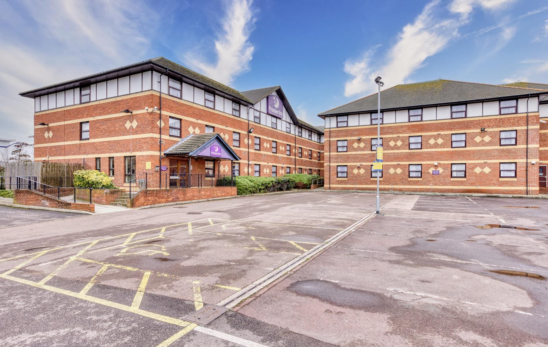 A brick building with a flat roof, a covered entrance, and a parking lot.