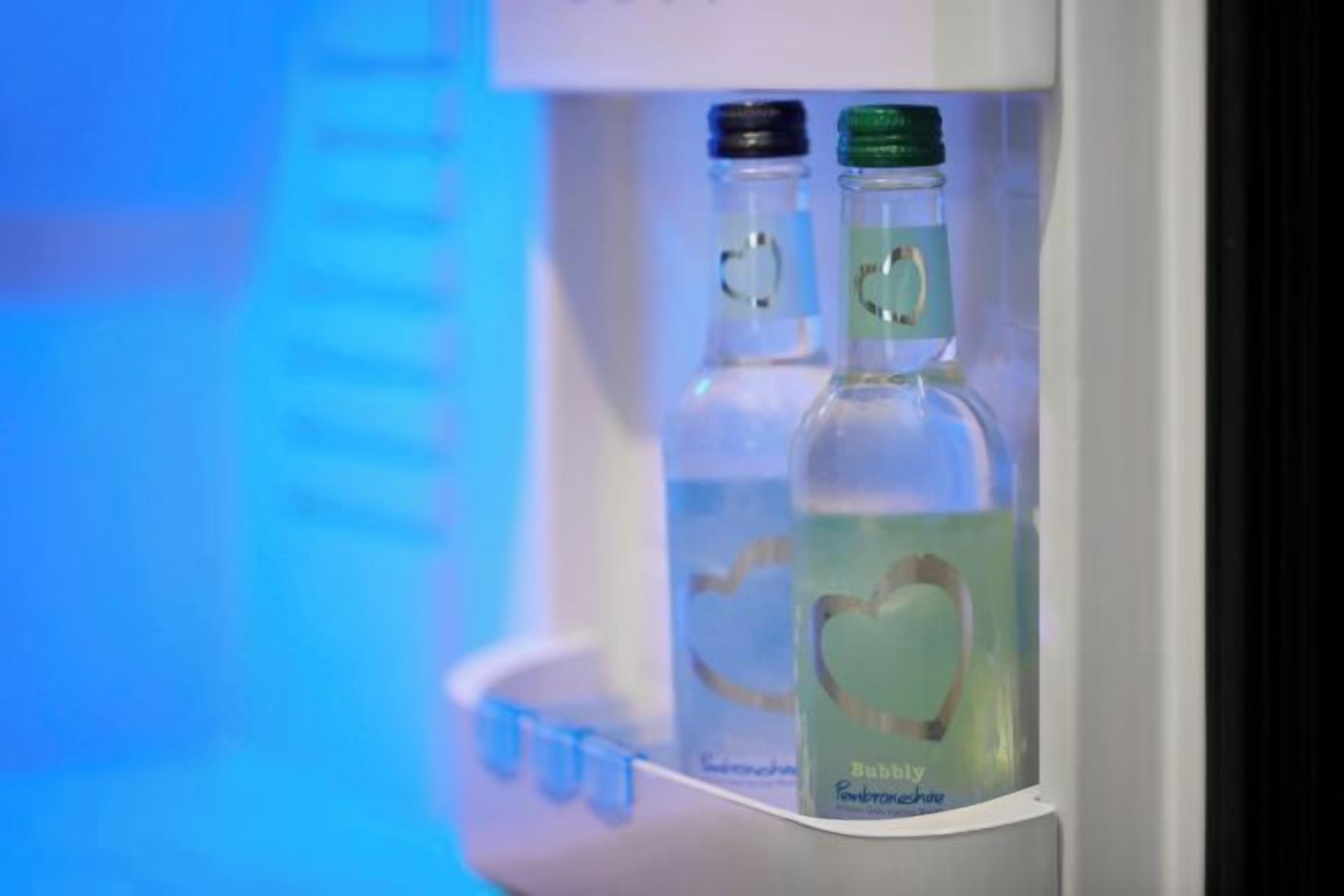 Un réfrigérateur contenant deux bouteilles d’eau et une bouteille de jus.