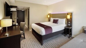 Quarto de hotel com uma cama grande, mesas de cabeceira, uma escrivaninha e uma cadeira.