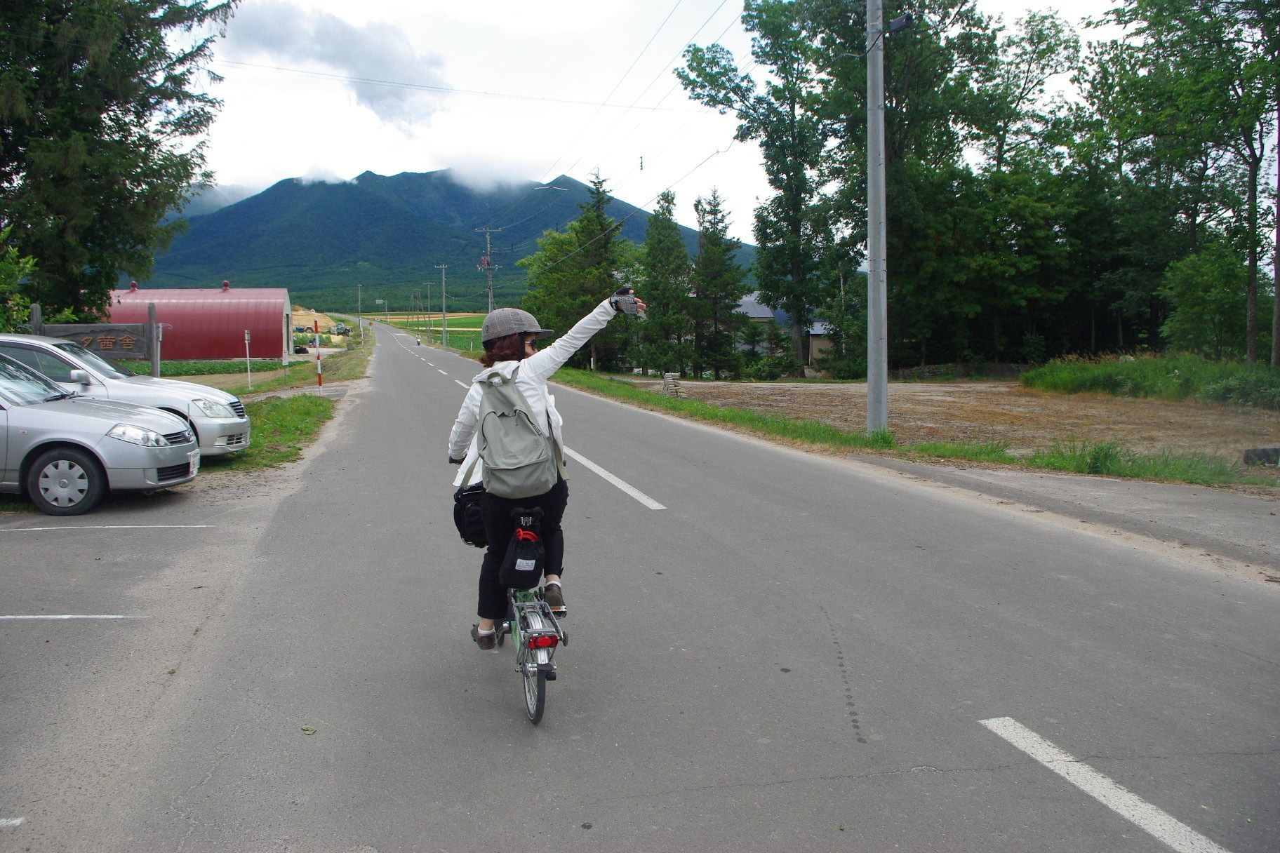 Una persona montando en bicicleta por una calle con coches estacionados al lado.