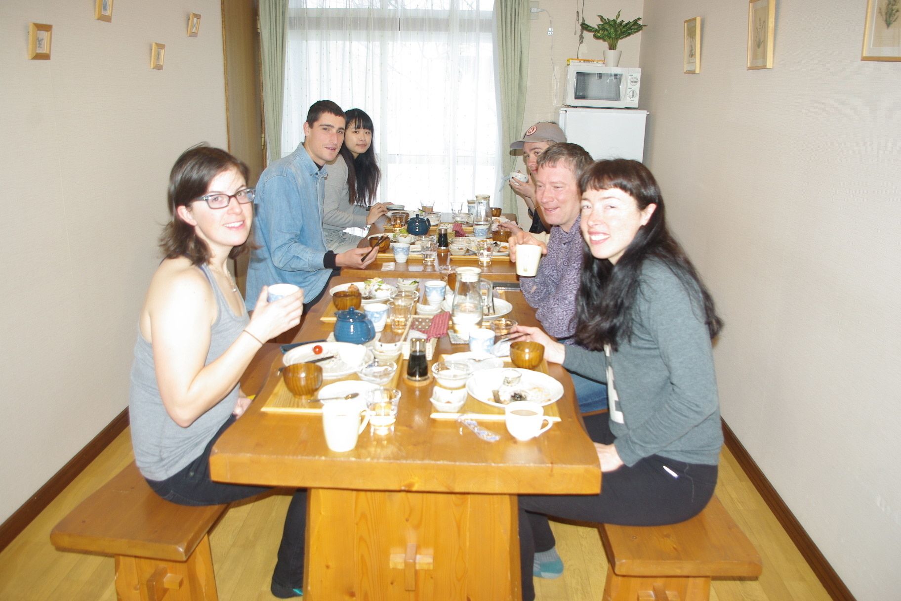 Una mesa de comedor con varias personas sentadas alrededor, rodeada de platos y vasos.