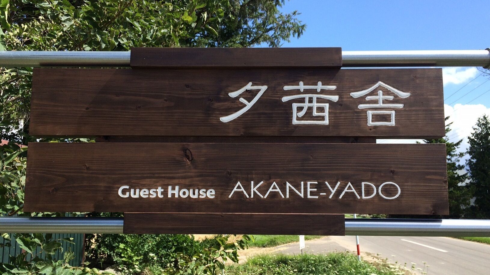 A wooden sign with "Guest House Akane-yado" written on it.