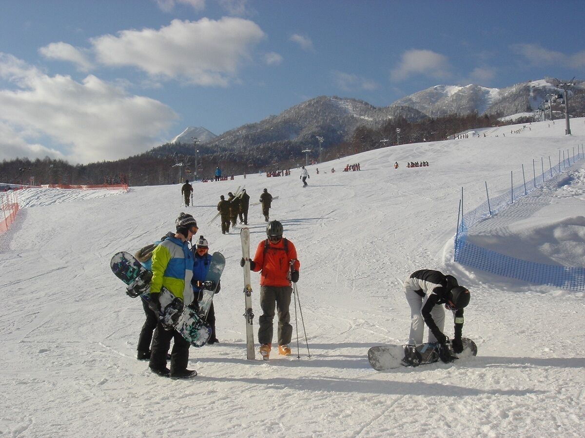 Pista de esquí nevada con esquiadores y snowboarders.