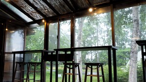 Una habitación con ventanas amplias, mesas de madera y taburetes.