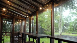 Un interior moderno con una larga mesa y sillas, ventanas amplias y un techo de madera.