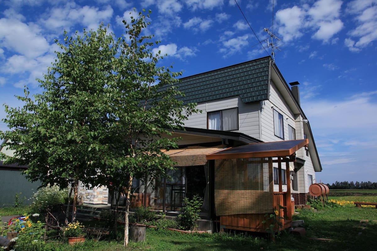 Une maison moderne à deux étages, dotée d’un toit en pente, de grandes fenêtres et d’un porche abrité.