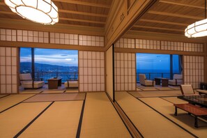 A traditional Japanese-style room with tatami flooring, sliding doors, and a view of the cityscape at dusk. - Ginrinsou (Otaru)