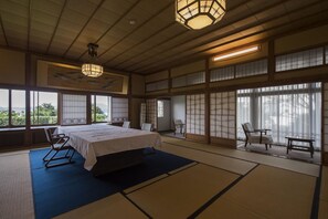 A traditional Japanese-style room with tatami flooring, a bed, a table, and chairs. - Ginrinsou (Otaru)