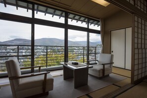 A room with a view of a cityscape, two chairs, a small table, and traditional tatami flooring. - Ginrinsou (Otaru)