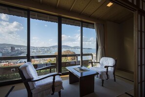 A balcony with a table and two chairs, overlooking a cityscape and water. - Ginrinsou (Otaru)