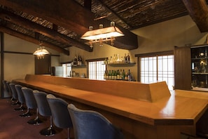 A bar area with a long counter, multiple chairs, and shelves with bottles. - Ginrinsou (Otaru)