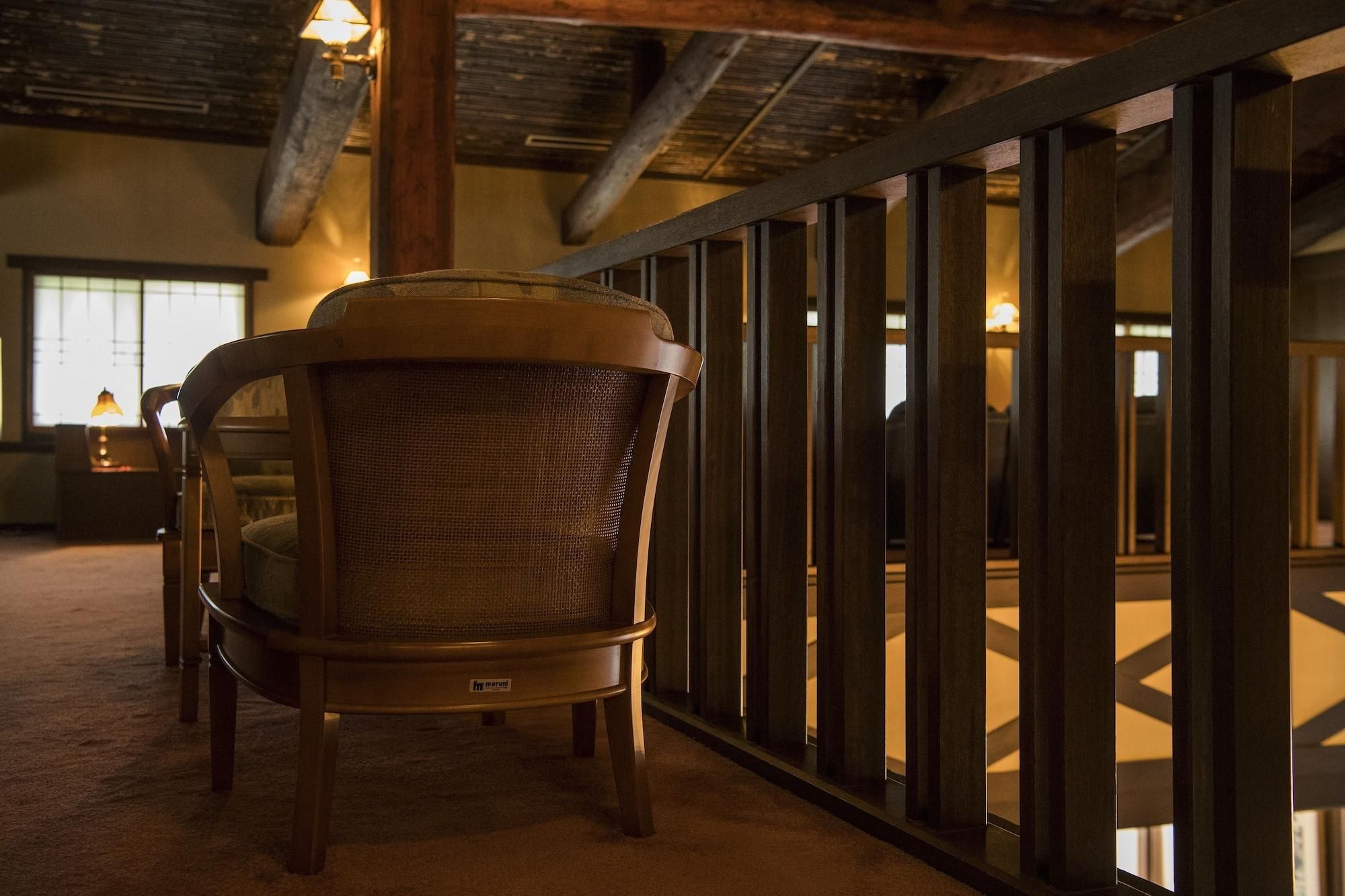 A chair with a woven backrest in a room with a high ceiling and exposed beams.