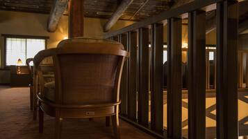 A chair with a woven backrest in a room with a high ceiling and exposed beams.