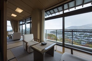 A hotel room with a balcony, a seating area with a table, and a view of a cityscape. - Ginrinsou (Otaru)