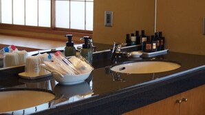 A hotel bathroom with a large sink, toiletries, and a mirror. - Ginrinsou (Otaru)