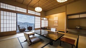 Um quarto japonês tradicional com tatames, painéis shoji e vista para o mar.